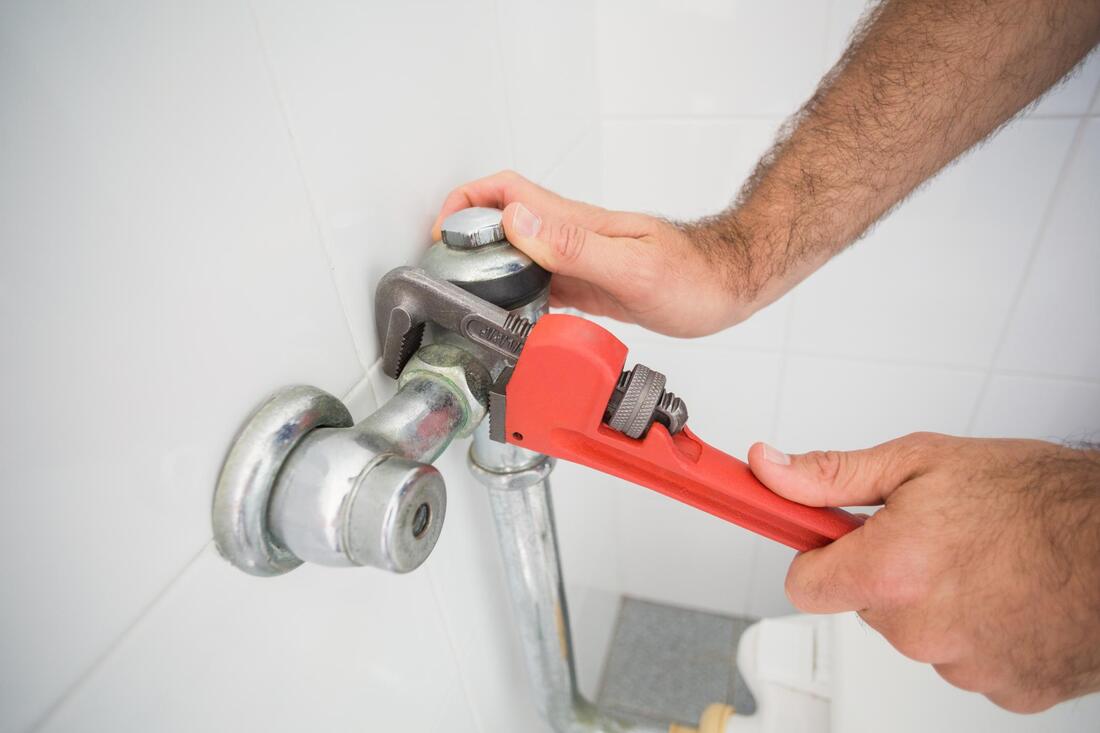 Picture a person's hands fixing a toilet in an industrial bathroom. Kitchen, Bath, and Basement Contractor working on a commercial job in Grand Rapids, MI.